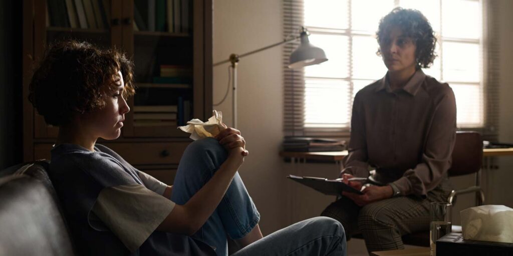 College student speaking with an addiction counselor in a private office